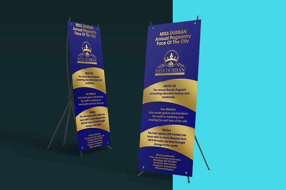 Two roll-up banner stands for the Miss Durban pageant in blue and gold, listing its mission and history