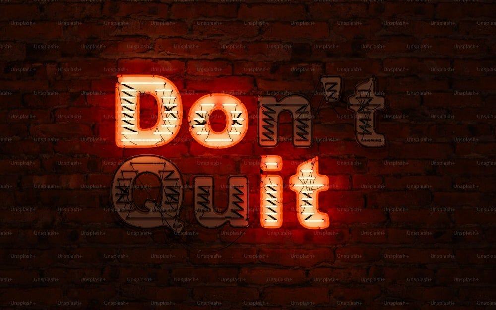 Neon sign reading Don’t Quit on a dark brick wall, with only the letters that spell Do it lit up