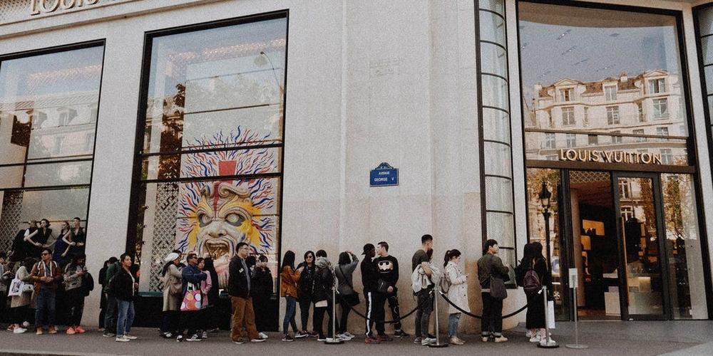 Shoppers lined up behind ropes outside a Louis Vuitton store