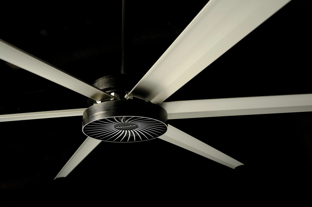 Large ceiling fan with long white blades against a dark background