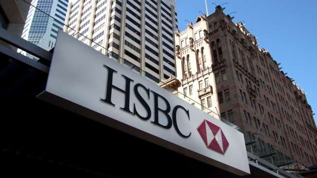 HSBC sign over a bank entrance, with city high-rise buildings behind