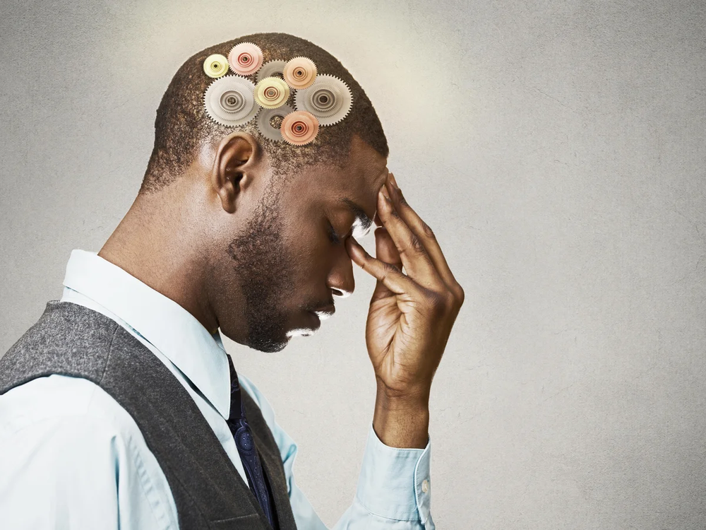 Man in profile pressing his forehead, with colorful gears drawn on his head