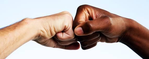 Two people with different skin tones bumping fists