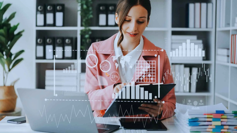 Woman reviewing a tablet at her desk, overlaid with floating charts and project data graphics