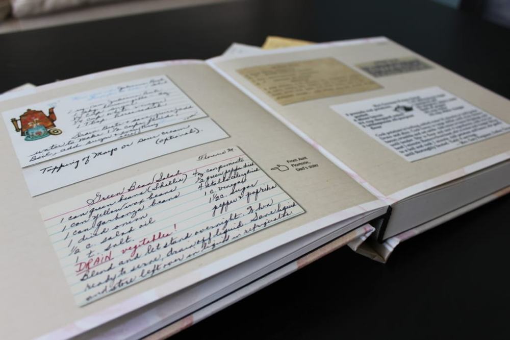 Open recipe album with handwritten and printed family recipe cards, including a green bean salad
