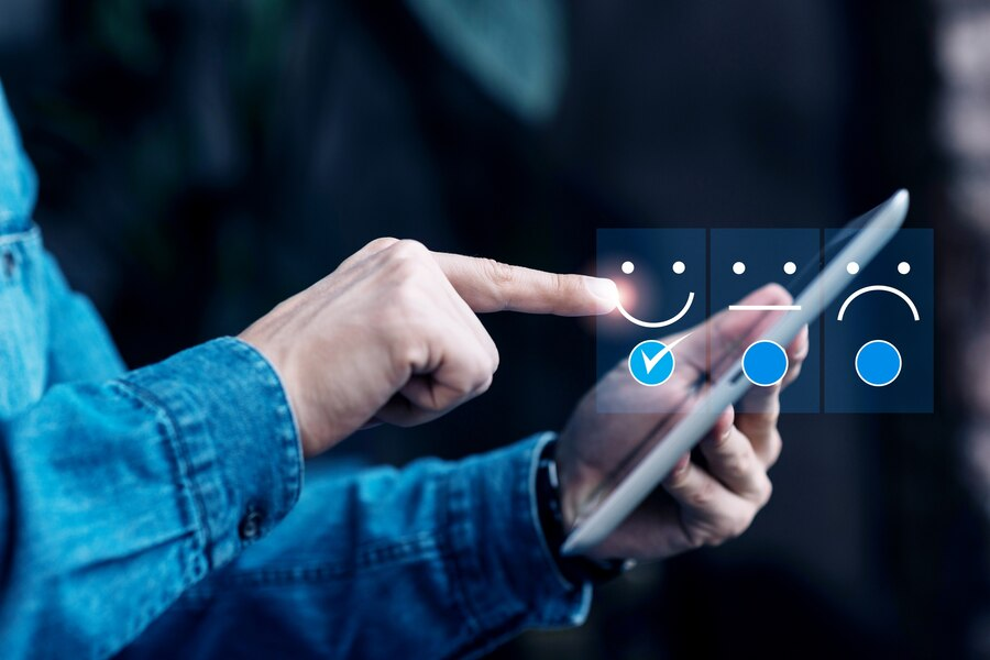 A hand tapping a smiling face on a tablet's satisfaction rating