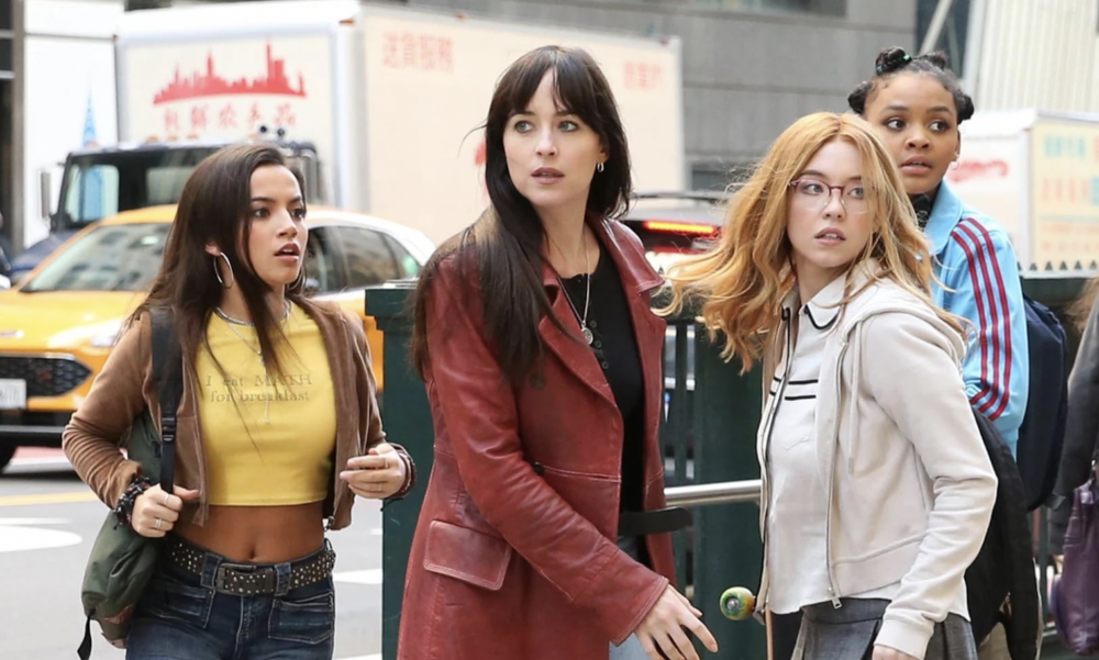Four young women on a busy city street look around warily, a yellow taxi and a truck behind them, in a Madame Web still