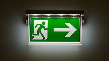 Lit green emergency exit sign with a running figure and an arrow pointing right