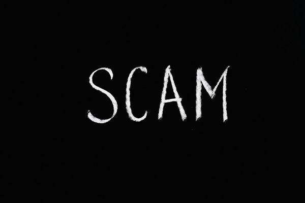 The word SCAM written in white chalk on a black background