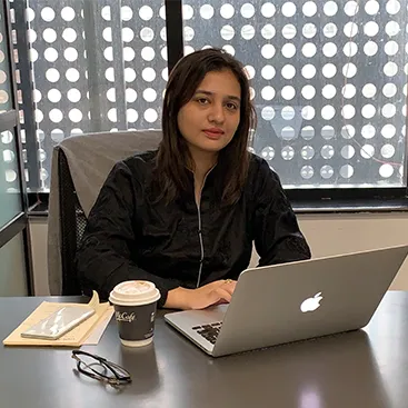 Aqsa Mirza, CMO, at her desk with a laptop and a coffee