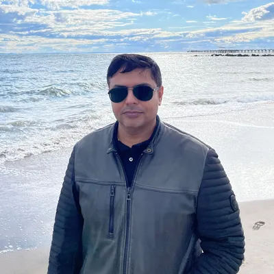 Ahmad Tayyab, Director (North America), on a beach in sunglasses and a leather jacket