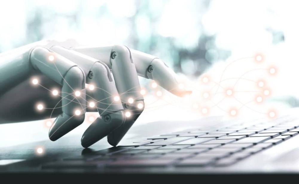 Robot hand typing on a laptop keyboard, surrounded by glowing network lines