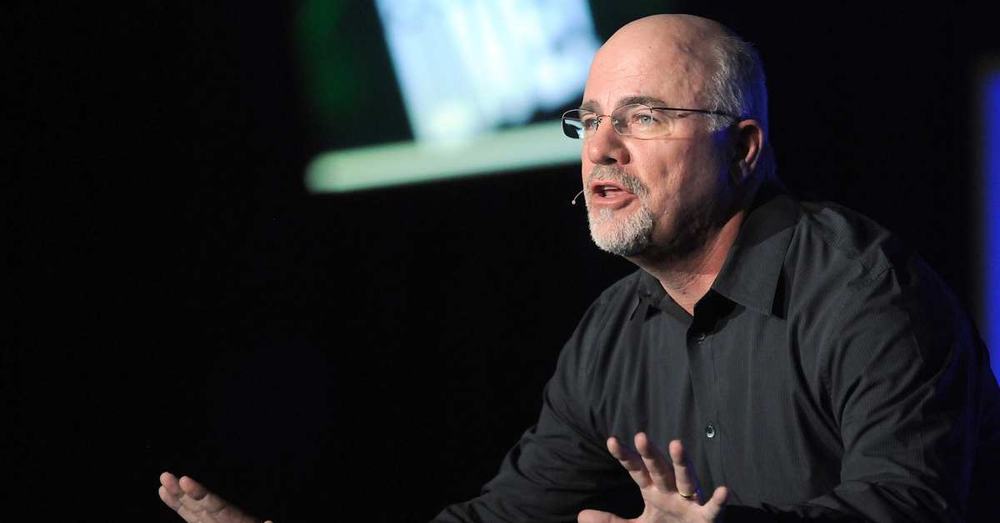 Dave Ramsey speaking on stage with a headset microphone, hands outstretched as he makes a point