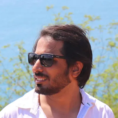 Khunshan Ahmad, CEO and CTO of EvolveDash, smiling outdoors in sunglasses