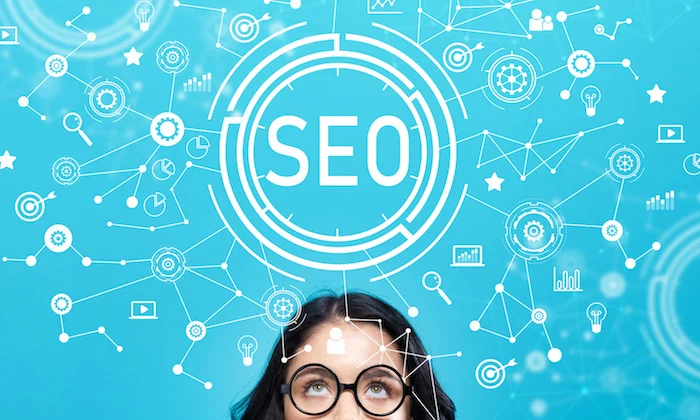 Woman in glasses looking up at a glowing SEO graphic surrounded by connected marketing and analytics icons