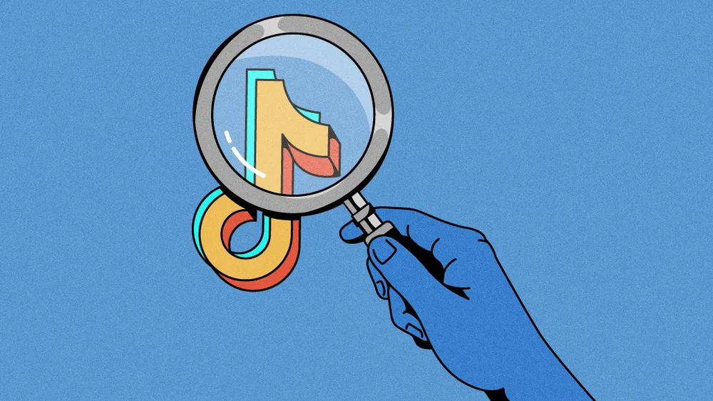 Hand holding a magnifying glass over the TikTok logo
